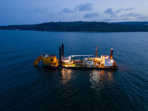 Aerial view of a dredge vessel with a dredging bucket, actively deepening the navigational fairway at sea, ensuring safe navigation.