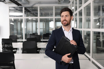 Happy real estate agent with leather portfolio indoors. Space for text
