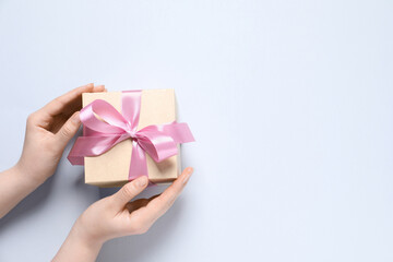 Woman holding gift box with pink bow on white background, top view. Space for text