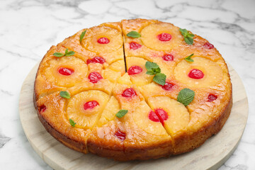 Delicious cut pineapple pie with cherry and mint on white marble table, closeup