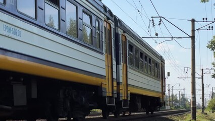 Suburban train travels through the countryside at a summer dusk. Long shot
