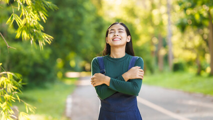 Happy young Asian woman relaxing outdoors, Enjoy beauty of nature and find inner peace on a sunny afternoon, relax time, love your self.