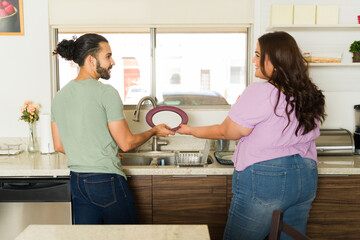 Boyfriend and girlfriend doing the dishes and sharing house chores