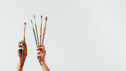 Artist equipment. Painting brush. Woman painter hands holding set of messy colorful paintbrushes...