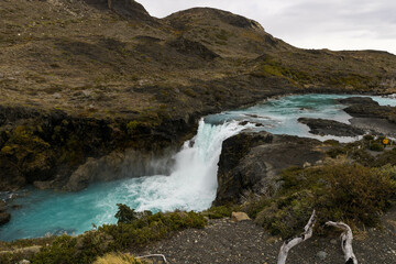 Explore the captivating beauty of a cerulean river cascading through the heart of Torres del Paine National Park. In this stunning image, the crystal-clear waters of the river flow with a serene, yet 