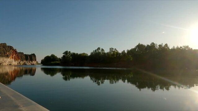 Sailing down still river showing reflection of trees on bank as sunset approaching  in Western Australia