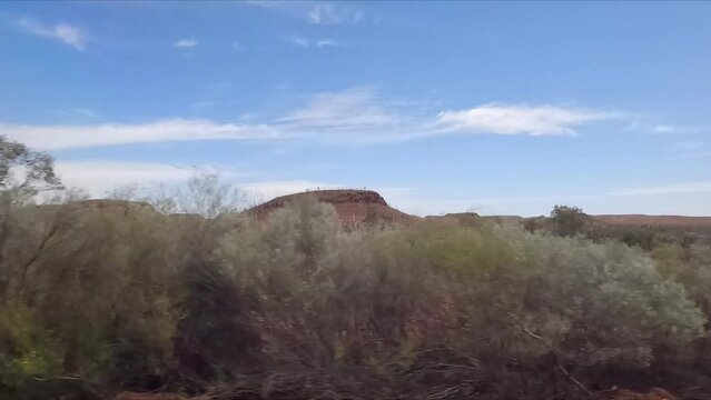 Driving along Western Australian highway passing through landscape with red mounds