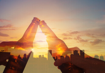 Hands toasting beer on rooftop city sunset background. Party and celebration concept.