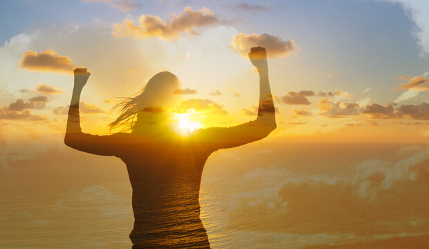 Strong victorious woman flexing in the sunrise. health and success concept. 