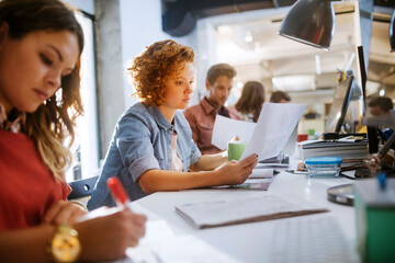 Young group of coworkers going over paperwork in the office of a startup company