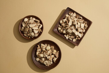 Top view of three wooden trays filled with sand ginger slices decorated on beige background. Photo for medicine advertising. Sand ginger is effective in treating digestive diseases.