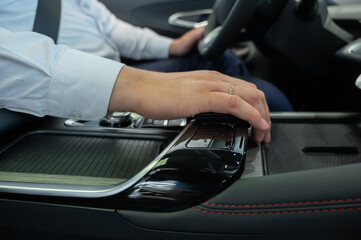 Close-up of a man's hands on the automatic transmission of a modern car. 