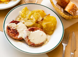 Appetizing roasted turkey breast steaks with Roquefort cheese sauce served with fried potato with onion.