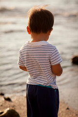 Fototapeta na wymiar Young boy standing on the beach, sunset, Hawaii
