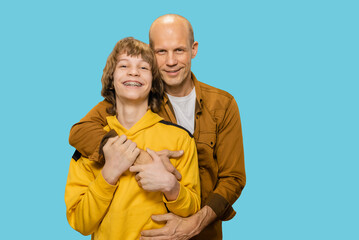 Young father hugging his teen son showing love and care, Smiling dad and teenage son showcase their strong connection with a heartfelt hug, brimming with joy.