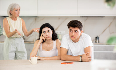 Obraz premium Portrait of an offended married couple in a home kitchen, which mature mother reprimand. Family conflict