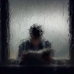 Foto auf Acrylglas a person framed by a window covered in raindrops, reading a newspaper © MASOKI