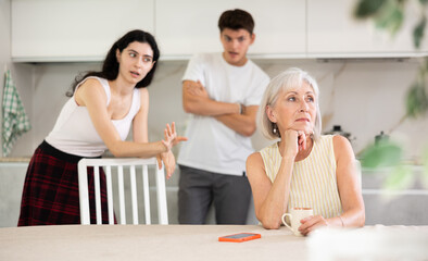 Adult children guy and girl are fighting with elderly woman mother. Family feuds, generational...