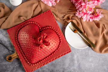 Heart Shaped red Cake with rose flowers, knife and fork served on board isolated on napkin top view of cafe baked food