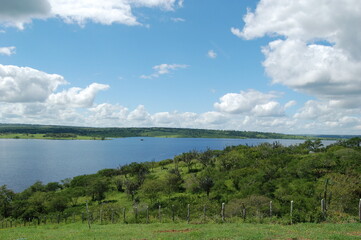 Lush green grass meadow under rural blue sky, grass texture and beautiful lake in the background. Beautiful morning light on green grass farm. the lake of Barragem da Pedra do Cavalo