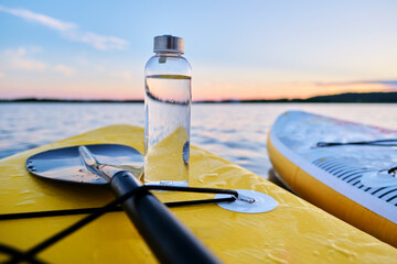 Water bottle on a yellow paddleboard.