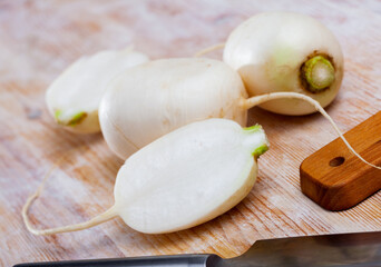 Whole and cut in half ripe turnips root crops on wooden background. Healthy nutrition concept