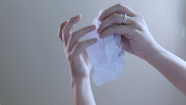 Looking up view, inside trash bin, focuses on person's hand, unfolding piece of paper scribbled with ideas, possibly signifying a mistake idea, and brings the concept of reuse for a circular economy.