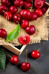 cherry on a black background. A large number of cherries with leaves on the table, on a black background. close-up.