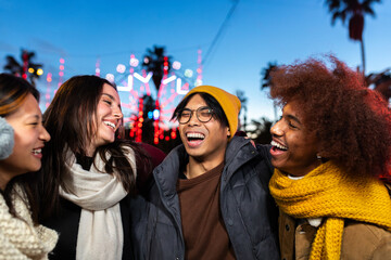 Multiethnic university friends laughing and having fun together during winter Christmas market...