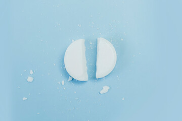 a white round tablet was cut into 2 equal parts. Pill broken on half. Pharmacy medicament concept.
