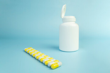 Yellow pills, plastic white bottle. Blue background with copy space for text. the concept of health medicine and pharmacy. Production of medicines.