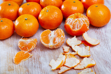 Peeled and whole fresh juicy clementines on wooden table. Concept of health benefits of citrus © JackF
