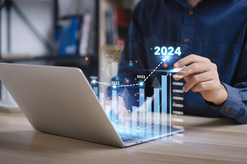 Businessman analyzes the graph of trend market growth in 2024 and plans business growth and profit increase in the year 2024. plan finances of the business - obrazy, fototapety, plakaty