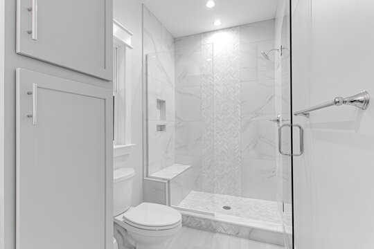 Clean Modern Primary Bathroom Glass Shower with Tile Walls and Grey Cabinetry. Stone Bench with Built In Shelves