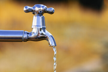 Metal tap with drain water in autumn outdoors