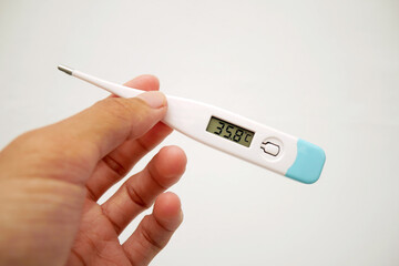 A man's hand holding a digital thermometer in her hand on a white background. A person looks at an...