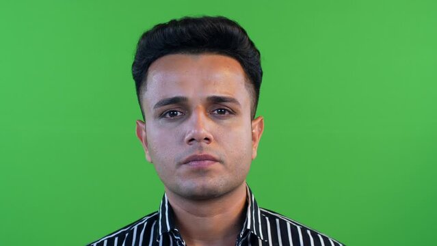 Closeup shot of a man lifting his face up and looking towards the camera with a serious face - green screen. Indian man looking up at the camera without any expression  green background  blank gest...