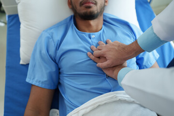 Obraz premium A male doctor uses his hands to pump a patient's heart with basic CPR in an emergency. Lying unconscious in bed. Unconscious. Cardiac arrest. Intensive care treatment concept.