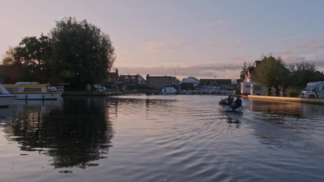 Pike anglers in the early morning as the sun starts to rise motoring up the River Bure in the village of Wroxham in the Norfolk Broads