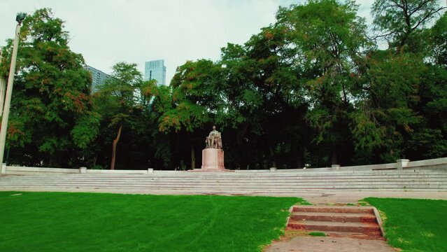 Abraham Lincoln monument in Chicago downtown, Illinois. Surrounded by trees in Grant Park. orbiting cinematic Aerial. Low angle, grass in front.