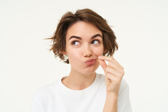 Image of young woman makes promise to keep secret, shows mouth zip gesture, puts a seal on her lips, dont talk sign, stands over white background