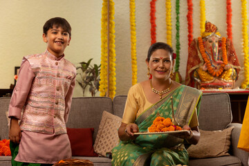 Maharashtrian woman holding a puja thali and her grandson standing beside