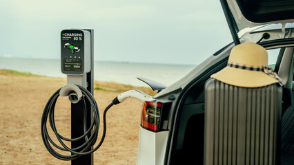 Road trip vacation traveling to the beach with electric car recharging battery with alternative eco-friendly and clean energy. Natural travel with EV car for sustainable environment. Perpetual