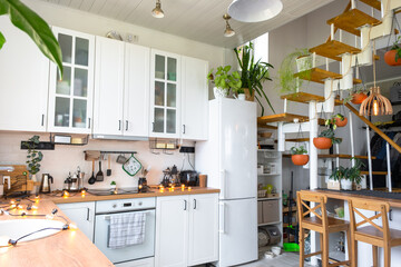 The general plan of a light white modern rustic kitchen with a modular metal staircase decorated...