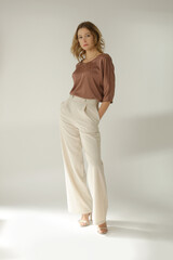Serie of studio photos of young female model wearing simple beautiful outfit, silk satin blouse and...