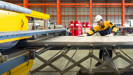 A diligent worker is engrossed in his task, carefully manipulating a vast sheet of metal, the gleam of effort and precision reflecting off its polished surface.