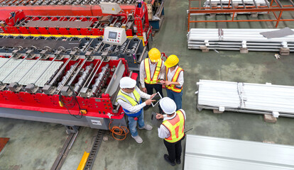 Senior engineer manager trains new employees within the metal sheet factory. Everyone wear safety...