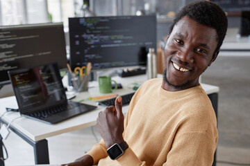 Portrait of African American successful programmer smiling at camera and showing thumb up