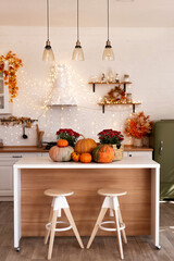 Autumn kitchen interior. Red and yellow leaves and flowers in the vase and pumpkin on light background