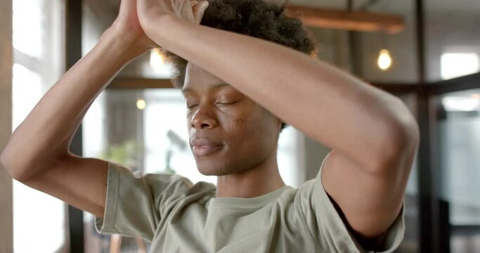 African american man doing yoga and meditating at home, slow motion